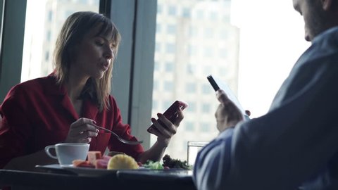 Young couple using smartphone during breakfast in restaurant
