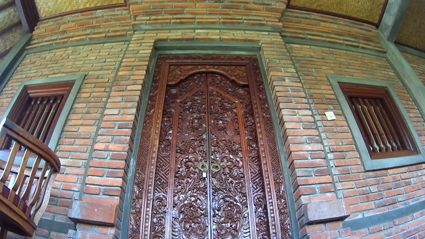 Opening and walking through hand crafted Balinese wood door.