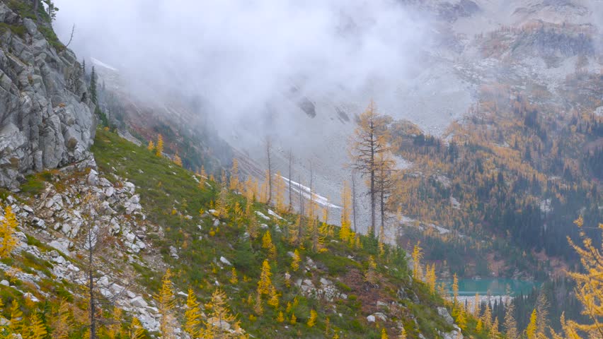 Clouds move gently over the spruce forest in the mountains. Blue Lake at the foot of the mountains.North Cascades National Park. Washington state. Landscape video.4K, 3840*2160, high bit rate, UHD