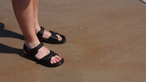 Close-up of a man's feet in the surf on a beach.