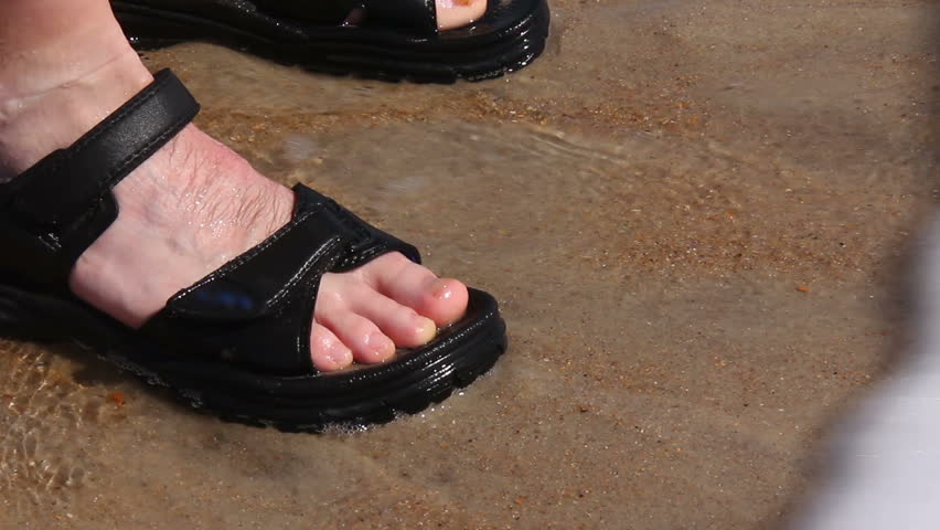 Close-up of a man's feet in the surf on a beach.