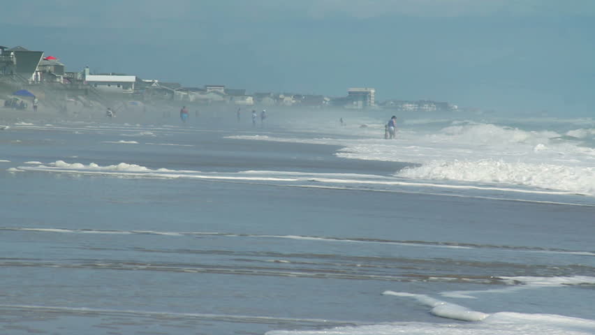 People frolic and play on the beach and in the surf on a warm summer's day.