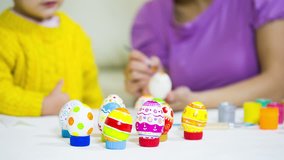 Kid painting Easter eggs with  mother