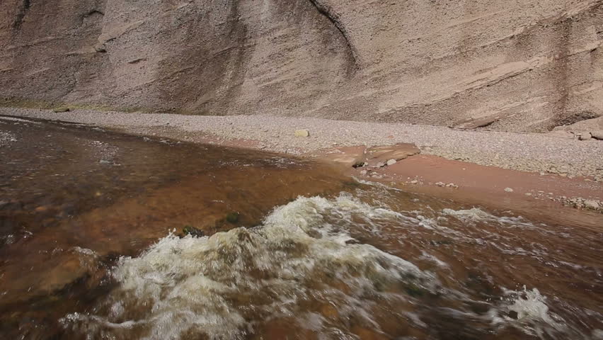 Vertical pan of beach stream and rock wall at low tide along Bay of Fundy at St. Martins, New Brunswick, Canada.