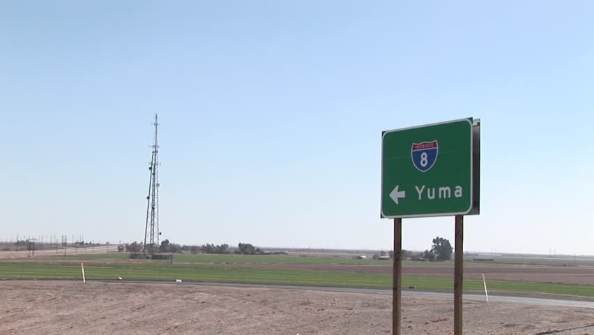 A truck drives by a road sign pointing to Yuma.