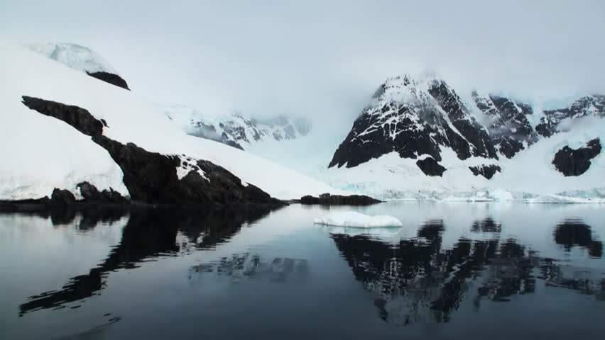 Moving Ice Floes and Ice Sheets in the calm Antarctic Sea, Reflection of Antarctica Mountain in water surface. Amazing beautiful views of Nature and landscape of snow, ice and white of Antarctic.