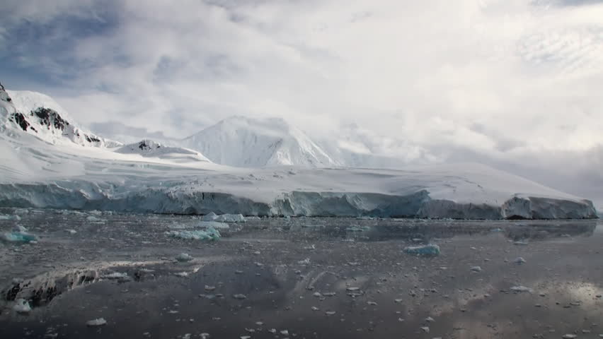 Moving Ice Floes and Ice Sheets in the calm Antarctic Sea, Reflection of Antarctica Mountain in water surface. Amazing beautiful views of Nature and landscape of snow, ice and white of Antarctic.