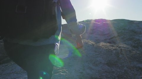 Girl with backpack runs to the end of cliff. Amazing sun flare.