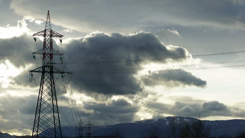 Electricity pylon standing out against a cloudy sky. Time lapse.