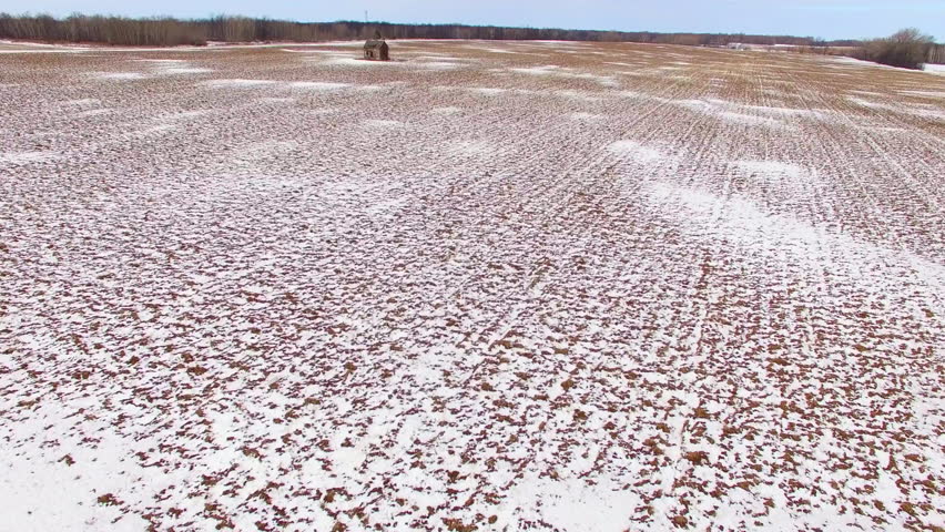 Lonely little old house in ruins in frozen Wisconsin farm field, aerial flyover.
