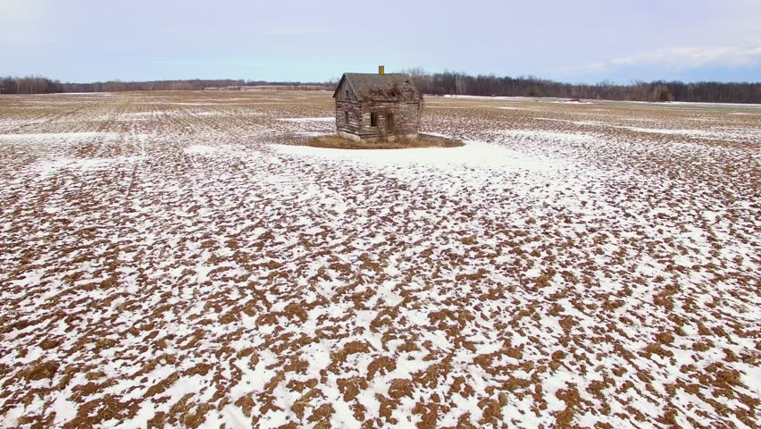 Lonely little old house in ruins in frozen Wisconsin farm field, aerial flyover.
