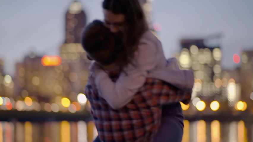 Playful Couple Dance On A Dock Across From City, Man Twirls His Girlfriend And Surprises Her With A Kiss On Her Hand, She Laughs Royalty-Free Stock Footage #15010474