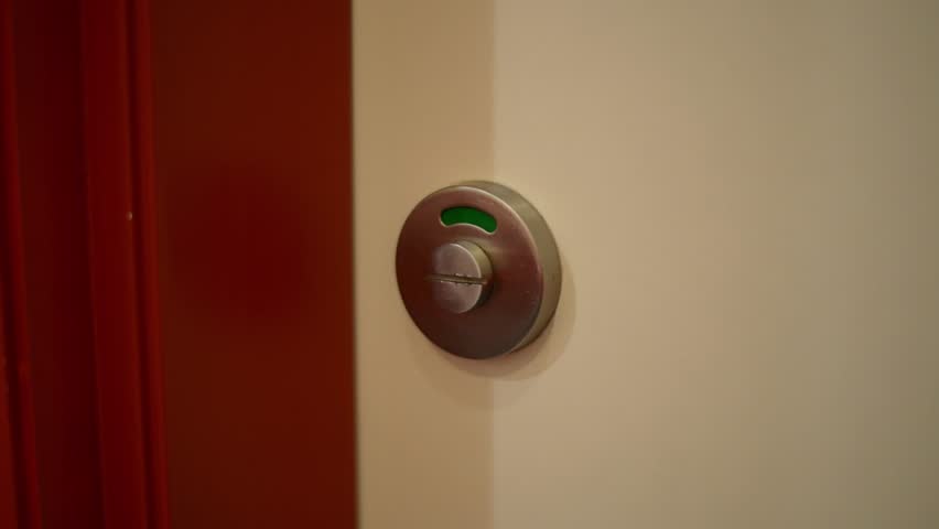 Close-up of a public toilet door lock which is green indicating cubicle is empty. Man opens door, enters, closes door and turns lock to red indicating cubicle is occupied or busy. Royalty-Free Stock Footage #15017959