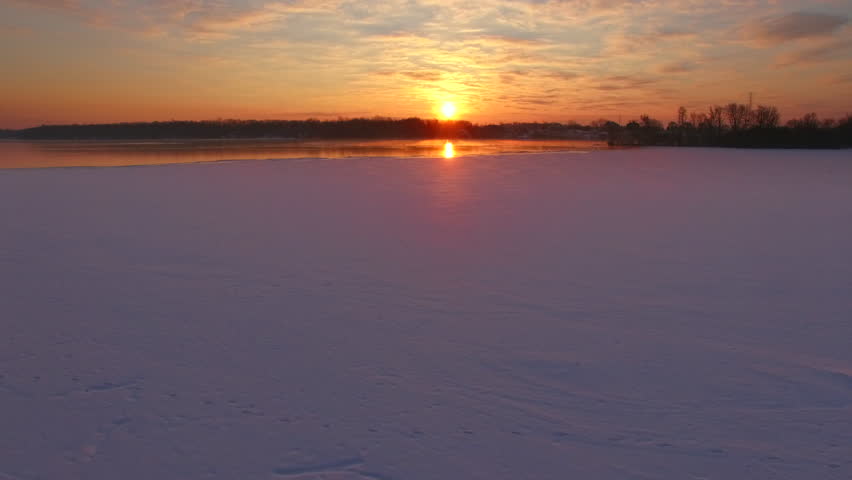 Amazingly colorful sunrise reflected in icy water surface, aerial view. Fox River, Wisconsin.