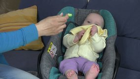 little baby with yellow bib eat vegetable pap sitting in car seat. Baby care Static tripod shot. video clip.