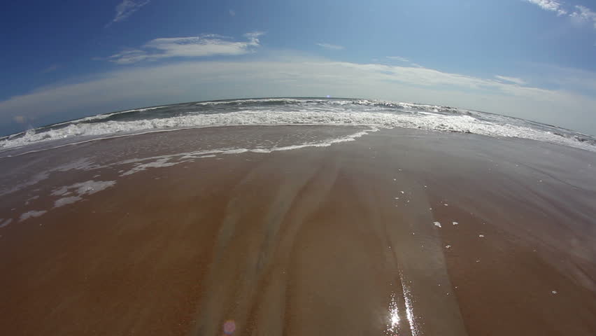 A fisheye look at the surf on a beach.