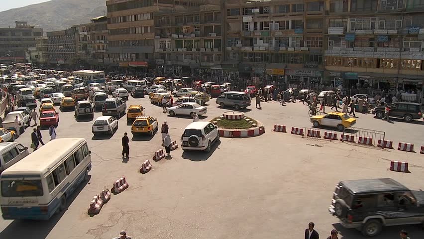 A wide establishing shot of downtown Kabul, Afghanistan with bus, taxi and vehicle traffic.
