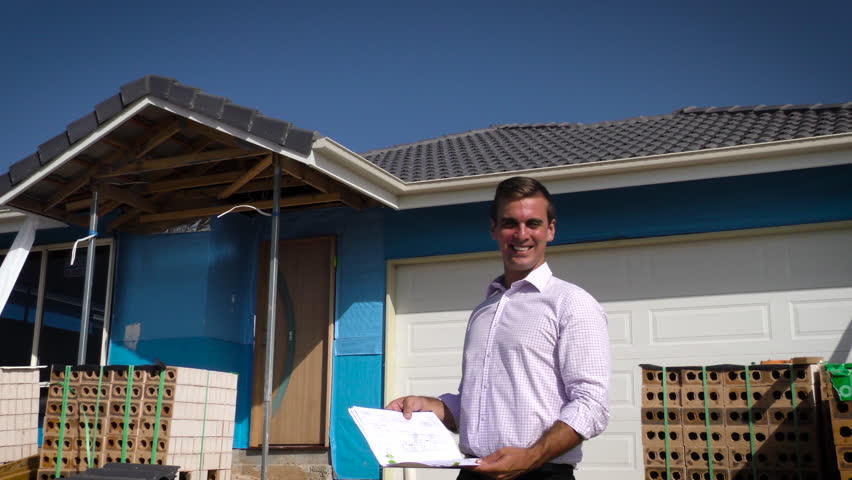 Young architect on construction site with plans. Slide.