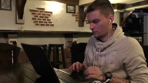 Young It specialist working on laptop computer by the table in cafe