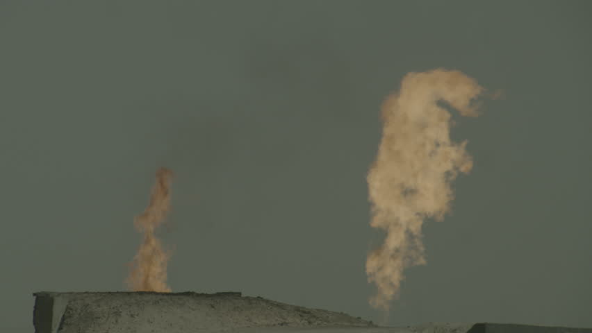 Kuwait Oil Industry. Close up on gas flares burning in the desert against a blue sky.
