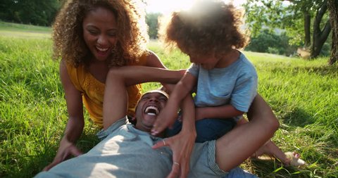 Young african-american family spending quality time toghether and relaxing in the beautiful picturesque park in the late afternoon