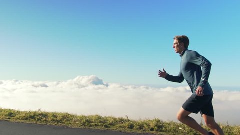 Young Man Running on Mountain Road at Sunset Above the Clouds. Slow Motion HD. Healthy Outdoor Lifestyle.