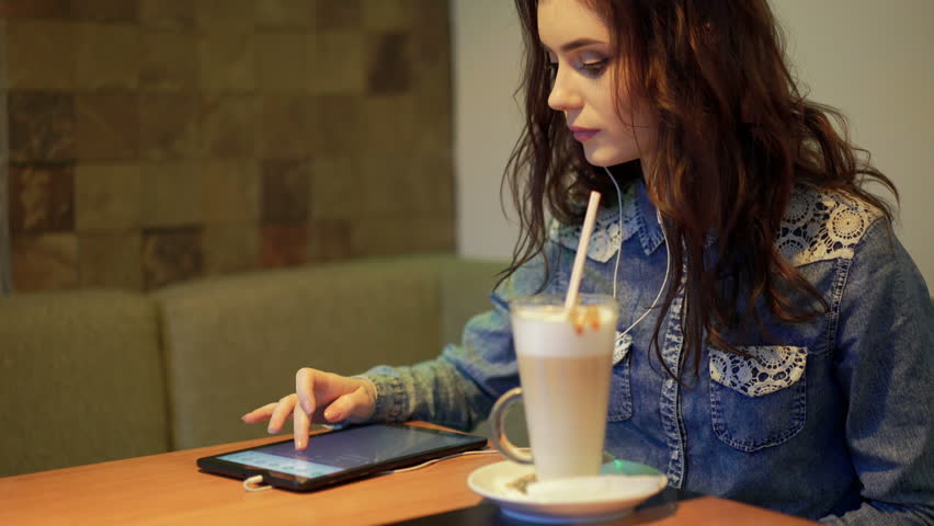 Beautiful girl listens to music in a cafe