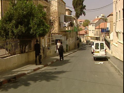 Jerusalem, Israel - 2006 - Orthodox Jews are walking in the streets of a Jerusalem neighborhood. The men are wearing black frock coats (kapotteh) with wide brimmed Fedoras or skullcaps.