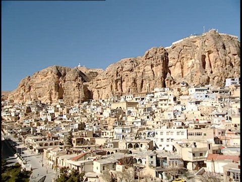 Maaloula, Syria - 2005 - Establishing shot of Maaloula showing buildings and houses clustered at the base of a rocky mountain.