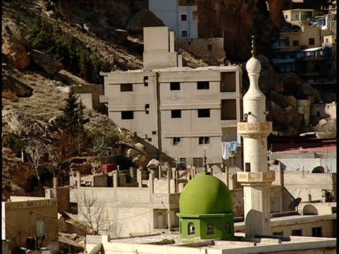 Maaloula, Syria - 2005 - Zoom out from a minaret to a church bell tower with Maaloula in the background. At the end of the clip the bell tower stands tall over a monastery built into a mountainside.