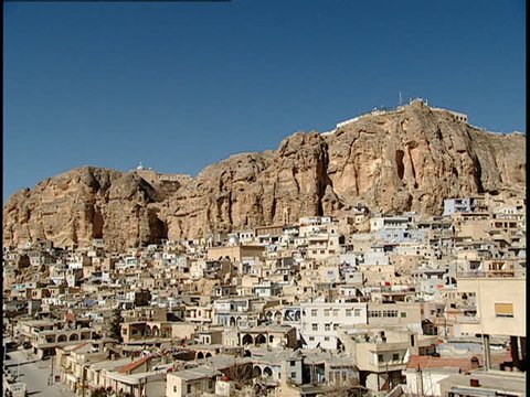 Maaloula, Syria - 2005 - Static shot of the city of Maaloula showing houses built into a dry mountainside with monasteries and churches on top of the hill in the background.