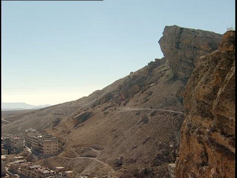 MAALOULA, SYRIA - CIRCA 2005: Tilt down showing the predominantly Christian town of Maaloula lying at the base of a steep, dry, craggy hill.