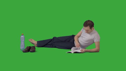 Attractive barefooted man is lying on side and reading book. Footage with alpha channel. File format - mov. Codec - PNG+Alpha Combine these footage with other people to make crowd effect