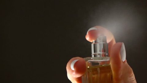 Woman hand with white manicure spraying some perfume, slow motion video