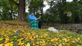 Senior Woman Reading Book in Autumn Park, Wide Angle, Dolly shot,  Side View