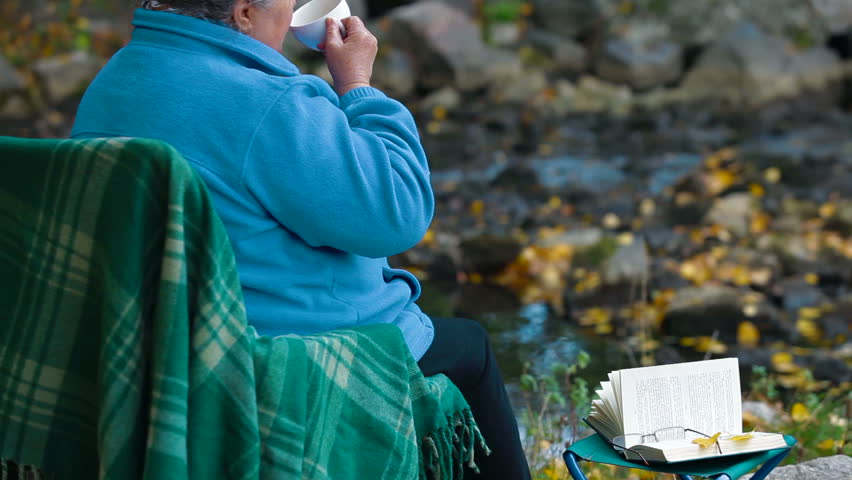 elderly woman drinking coffee from a cup at Autumn park, Side View