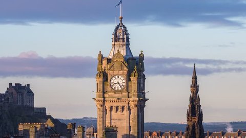 Time lapse footage of the Balmoral Clock at sunrise, viewed from Calton Hill. Edinburgh Castle and the Walter Scott Monument in the background.  Edinburgh, Scotland