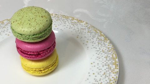 Three different colored macaroons are in the porcelain plate.