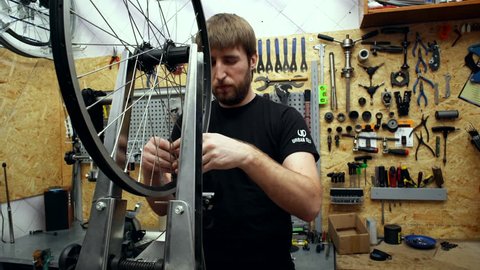 Mechanic repairing wheel in bicycle's workshop. Close up Stock Video