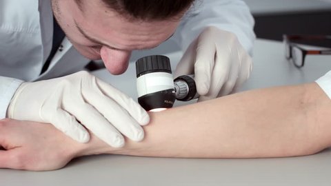 Caucasian male dermatologist examines a patient's skin in Dermatoscope