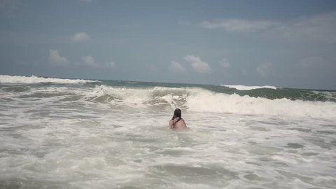Half naked woman jumps into ocean waves