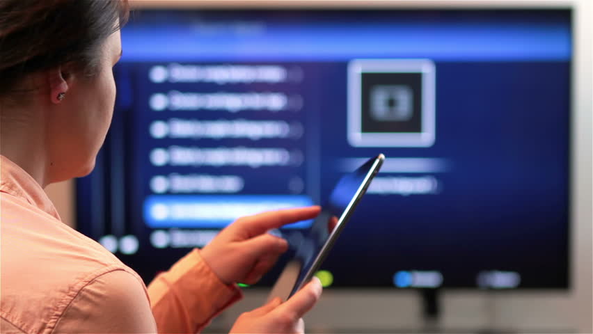Woman watches television while holding and tapping on a tablet computer device. | Shutterstock HD Video #15094024