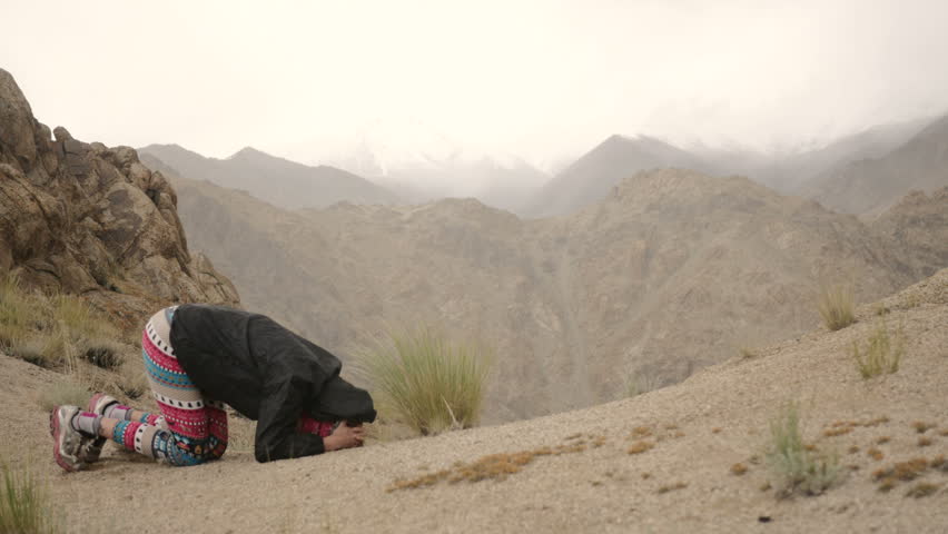 Yoga girl doing headstand in mountains in rain