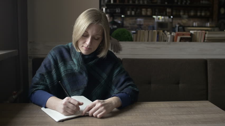 a girl writing in a notebook in cafe