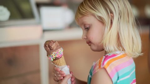Little Girl Enjoys Chocolate Ice Cream Cone With Sprinkles In Local Ice Cream Shop 