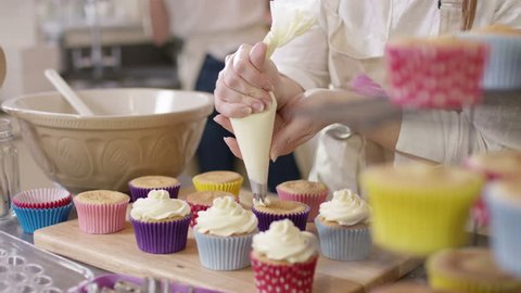 4K Woman with home bakery business piping cream onto cupcakes