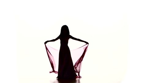 Pretty young woman starts dancing belly dance with colored shawl, on white, slow motion