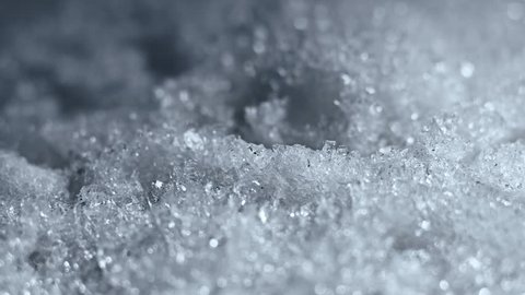 Melting Snow / Melting Ice / Melting Iceberg / Global Warming Effect. Macro time-lapse shot of shiny melting snow particles turning into liquid water. Static framing. (av26833c)