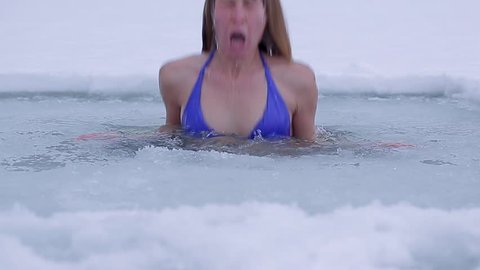 Young lady swimming in an ice hole during winter
