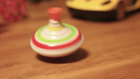 Defocused toy spinning gyroscope on brown floor